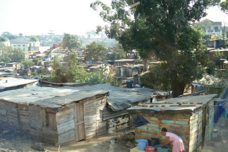 Urban slum in the developing world with woman washing clothes.